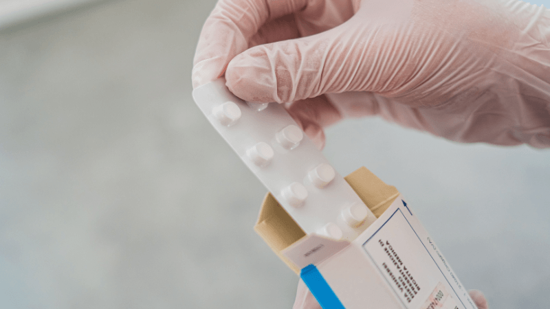 Healthcare professional handling prescription medication for pharmacology review study materials.