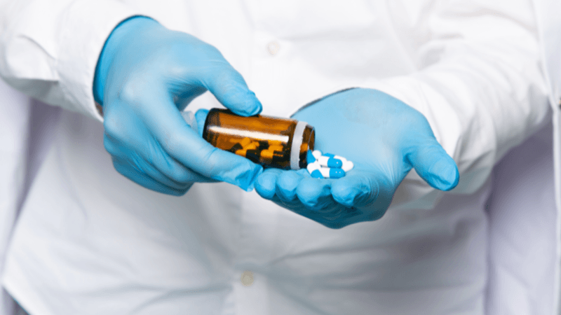 Pharmacist or nurse dispensing medication capsules for pharmacology and clinical study review content.