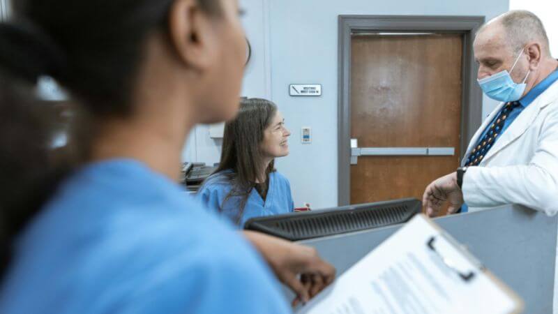 Healthcare professionals in discussion at a hospital reception.